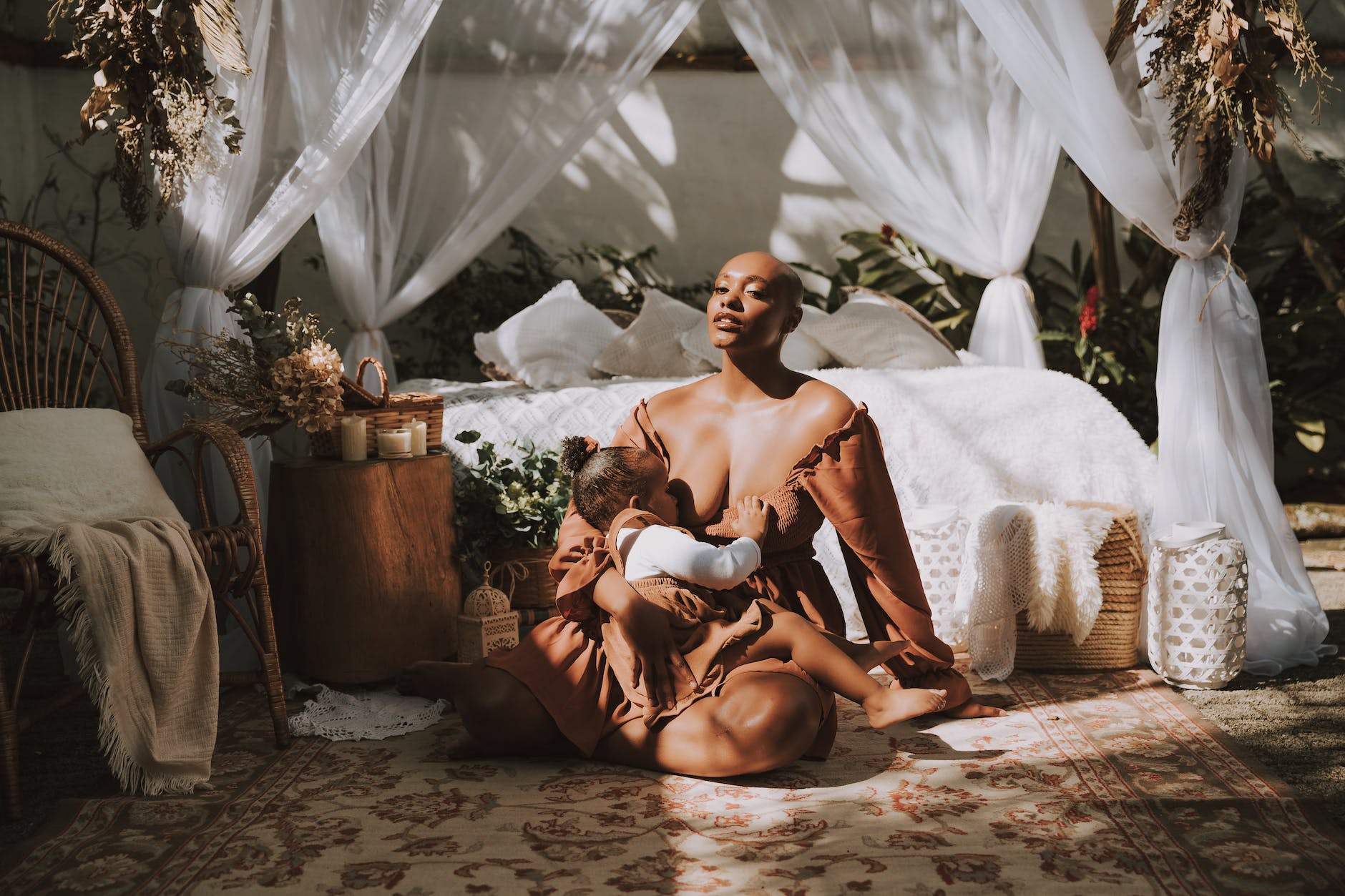 young woman breastfeeding a baby daughter on a bedroom rug